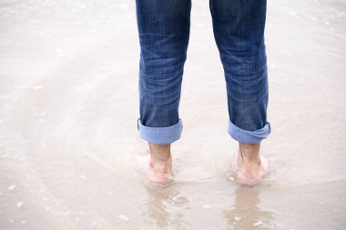 Genç adam denizde sabah ayakta