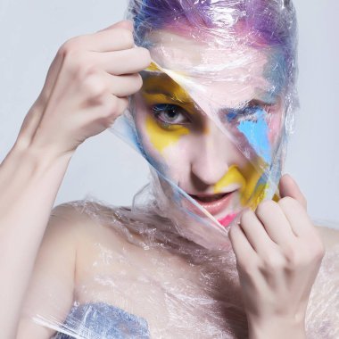 Genç kadın yüzü plastik boya ile. polyethylene.halloween vücut sanatı ambalaj kız boyalı rengi