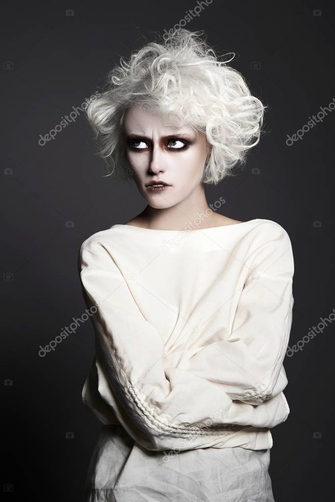 young woman with scary clown make-up for halloween.blonde girl with white skin psycho person for halloweem masquerade