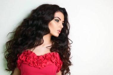 Kırmızı elbiseli güzel esmer genç kadın. Studio moda kız güzellik portresi. sağlıklı kıvırcık saç 