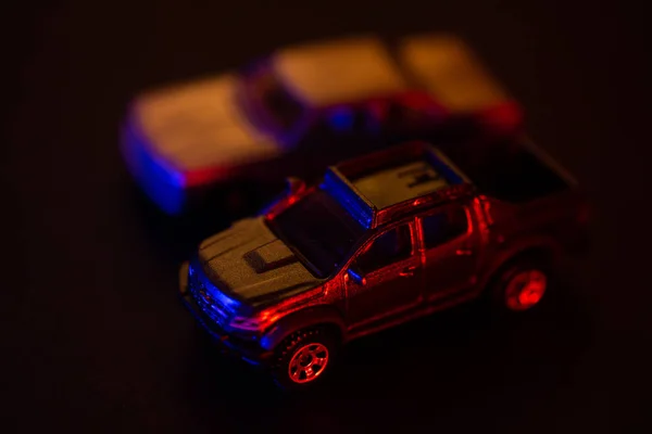 Automobili giocattolo sotto luce rossa e blu — Foto Stock