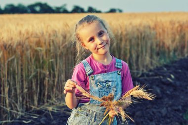 Neşeli kız buğday alanıyla yakınındaki bir yolda eğleniyor