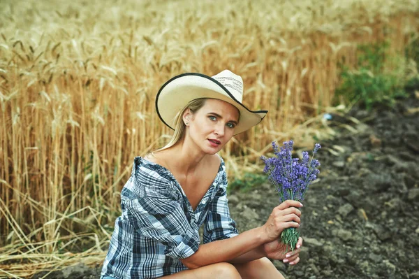 Buğday alanıyla bir yürüyüş için rahat kıyafetler genç kadın. Çiçekli lavanta tutan kız