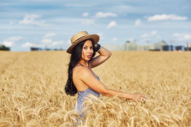 Buğday alanında bir yolda hafif yaz elbiseli Genç romantik kadın