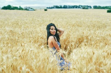 Buğday alanında bir yolda hafif yaz elbiseli Genç romantik kadın