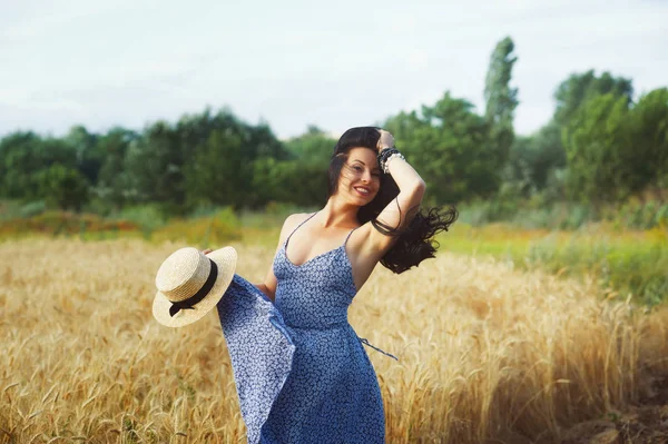 Buğday alanında bir yolda hafif yaz elbiseli Genç romantik kadın