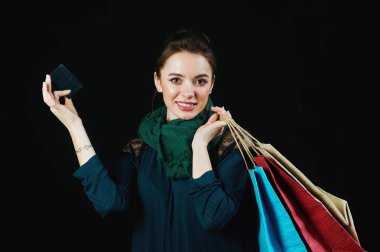 Alışveriş torbaları ve kredi kartı Studio koyu arka plan üzerinde çekici genç kadın