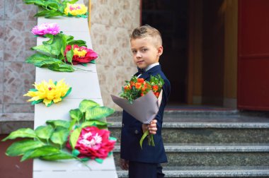 Bir buket çiçek güzel çocuk. Bir çiçek tutan bir birinci sınıf öğrencisi. Takım elbiseli şık çocuk