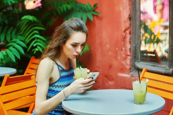 Cep telefonu vintage kafede oturan genç kadınla. Kız modern teknoloji kullanır