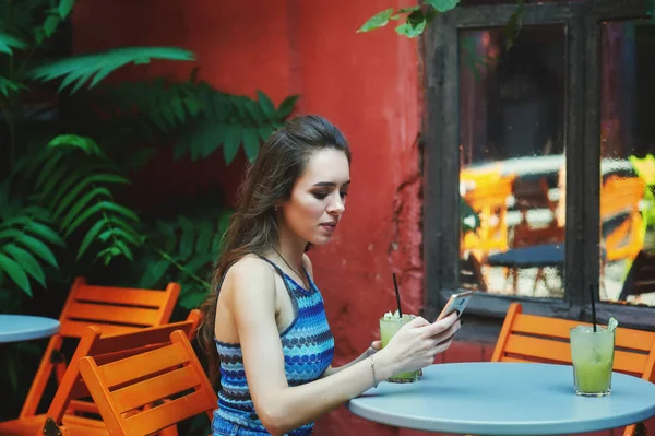 Cep telefonu vintage kafede oturan genç kadınla. Kız modern teknoloji kullanır