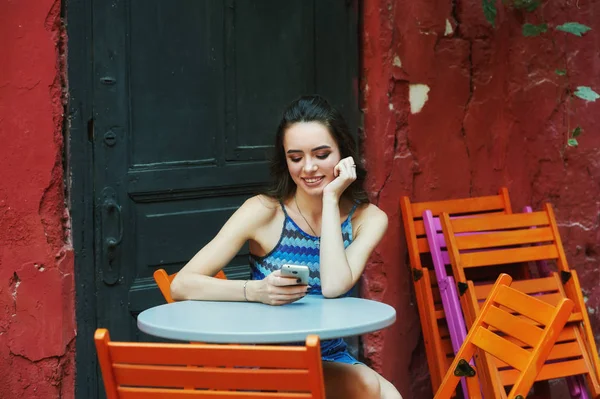 Cep telefonu vintage kafede oturan genç kadınla. Kız modern teknoloji kullanır