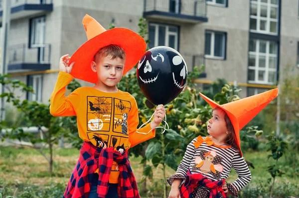 Funny kids in hats for Halloween outdoors . The day of the feast of Halloween