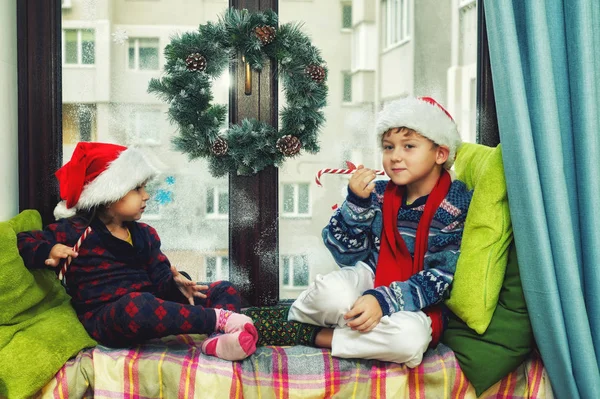 Веселі Діти Чекають Різдво Брат Сестра Вікні Одягнені Капелюхи Санта — стокове фото