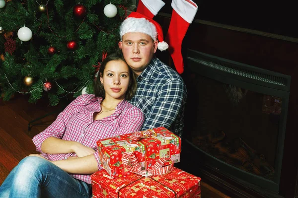 young couple in love on Christmas eve . Young people in plaid shirts and Santa hat in the house