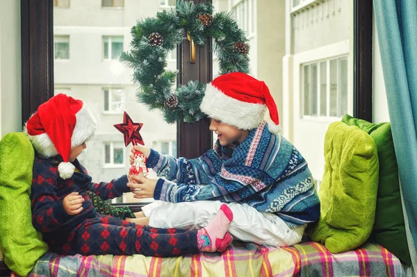 Веселі Діти Чекають Різдво Брат Сестра Вікні Одягнені Капелюхи Санта — стокове фото