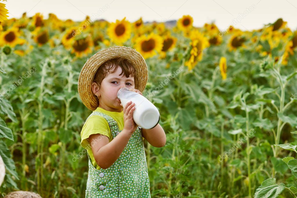 little girl drinking milk from a bottle in nature