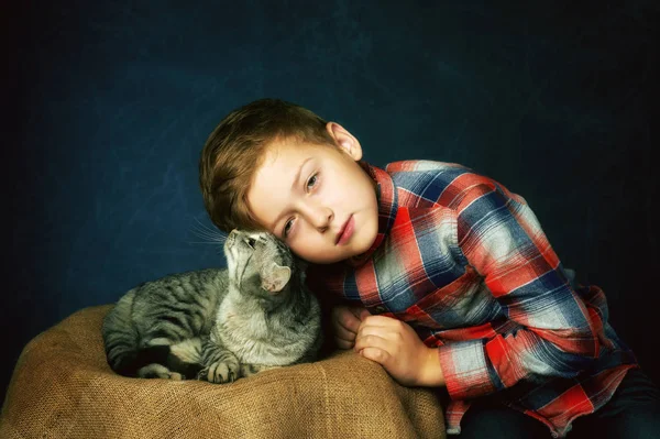 一个男孩的工作室肖像与猫在黑暗的背景 — 图库照片