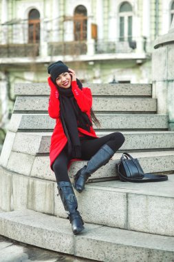 Kırmızı paltolu genç güzel bir moda kadın portresi. Bir şehir sokak poz model