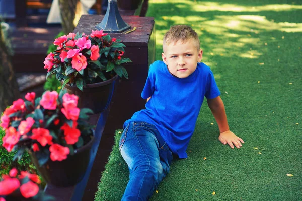 一个男孩坐在带鲜花的露台上的肖像 — 图库照片
