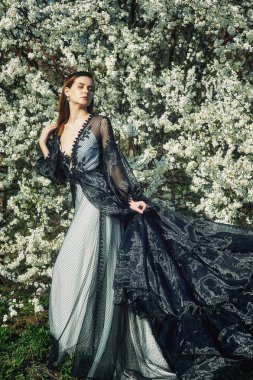 Bir gece elbiseli Genç güzel moda kadın portresi. Kız bir çiçeklenme bahçede poz