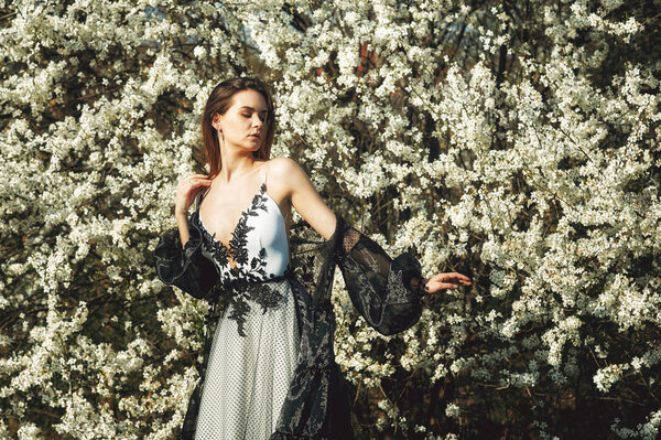 Portrait of a young beautiful fashionable woman in an evening dress . Girl posing in a blooming garden