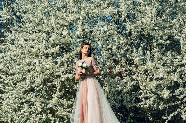 Portrait of a young beautiful fashionable woman in an evening dress . Girl posing in a blooming garden