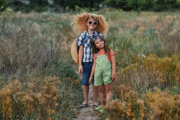 Boy and girl on a summer walk in the countryside .Beautiful children with sunglasses . Brother and sister on a summer walk