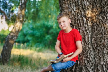 Parkta kitap okuyan çocuk. Okul dışı eğitim kavramı. Açık hava rekreasyon