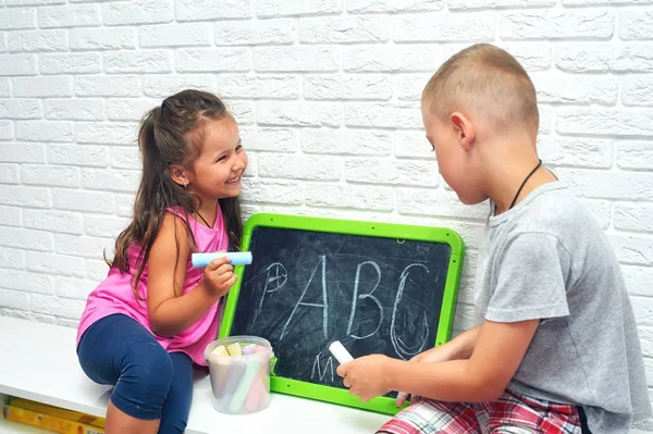 子供は手紙を覚える 兄は姉のアルファベットを教えている 学校外教育 ロイヤリティフリーのストック写真