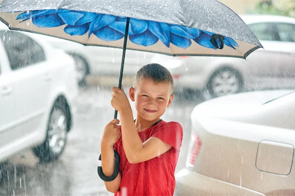 Portrait of a boy with an umbrella in the city .Warm summer rain