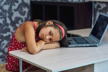 Laptop yorgun çocuk, bir dizüstü bilgisayar üzerinde çalışan yorgun küçük bir kız .