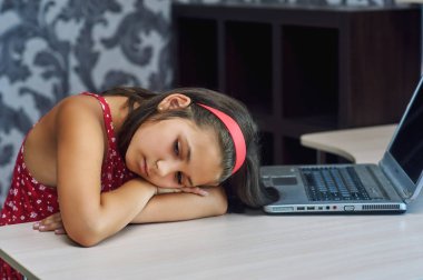 Laptop yorgun çocuk, bir dizüstü bilgisayar üzerinde çalışan yorgun küçük bir kız .
