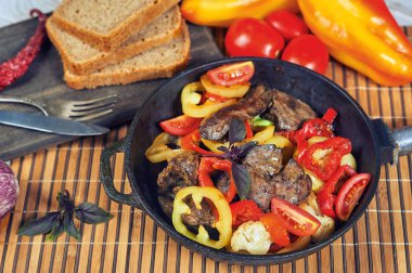 Masada bir tavada sebze ile Kızarmış tavuk ciğeri.