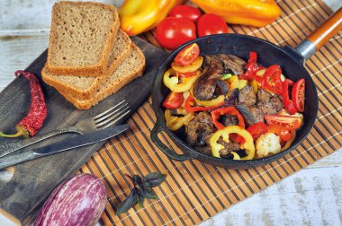 Masada bir tavada sebze ile Kızarmış tavuk ciğeri.