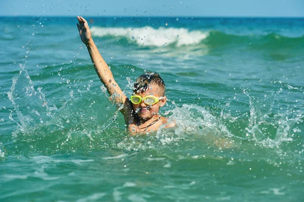 Denizde yüzen küçük bir çocuk. Sahil beldesinde mutlu çocuk