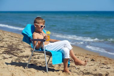 Sahilde neşeli çocuk. Çocuk serinletici bir içecek ile bir bardak tutuyor .