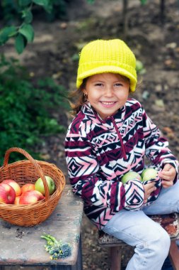 Bahçede elma bir ürün ile mutlu bir küçük kız portresi