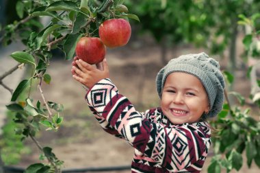 Bahçede elma bir ürün ile mutlu bir küçük kız portresi