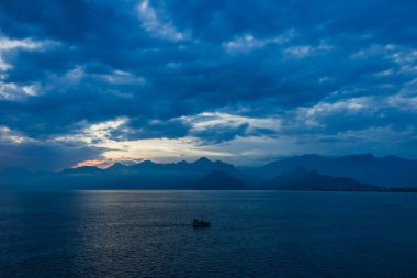 Doğal deniz arka planda küçük gemi ile seyahat turistler. Güzel günbatımı güneşli deniz suyu, dağlar, Yelkenli Yat bulutlu kabarık gökyüzü. Yatay renkli fotoğraf.