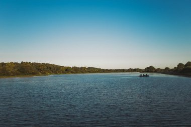 Çok güzel bir sabah nehir manzara siluet geleneksel ahşap tekne ve içinde balıkçılık çubuklar ile oturan üç adam ile. Mutlu tatil kavramı. Yatay renkli fotoğraf.