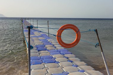 Alan yaz tropik sahilde Yüzme için kırmızı lifebuoy ve halatlar geçit kapalı. Yatay renkli fotoğraf.
