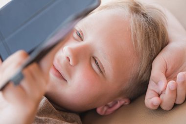 Çocuk bir şey ilginç ve komik modern smartphone cep telefonu ile yaz güneşli kumsalda açık yalan izliyor. Yatay renkli fotoğraf,