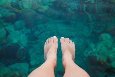 Kristal mavi su altında kadın pedicured bacak closeup üstten görünüm. Kadın duba birçok renkli balık ayakları yüzme izlerken zevk otel Resort oturur. Bakış açısı yatay fotoğraf.