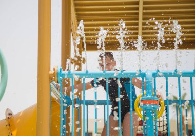 Aquapark, su kaydırağı mutlu oynamak mutlu neşeli Genç beyaz boy gülümseyerek. Yaz plaj tatil. Dikey renkli fotoğraf.
