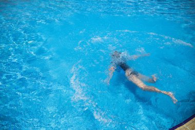 Üstten görünüm bir genç çocuk su altında güneşli yaz açık havada otel resort havuzda yüzme. Yatay renkli görüntü.