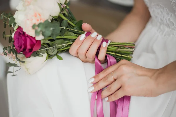 家の内部に一人で座っている若い花嫁の手に美しいカラフルな結婚式の花 美しいブライダル マニキュアとの婚約指輪の爪 水平方向のカラー写真 — ストック写真