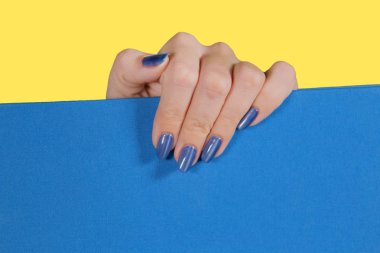 Beyaz kadın el ile parlak parlak modern mavi jel Lehçe portre üstten görünüm. Manikürlü tırnaklar yetişkin kadın sarı ve mavi arka plan izole makro. Yatay renkli fotoğraf.