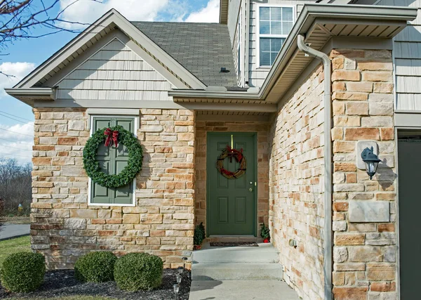エバー グリーンのクリスマス リースとドアにグレープバイン花輪を捧げると黄褐色の石造りの家のコーナーの入り口を飾る — ストック写真