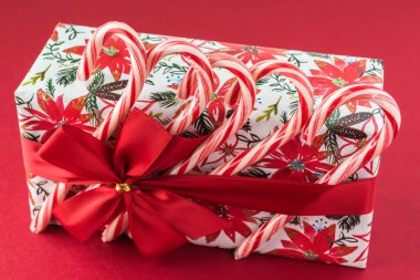 Şeker kutusu Noel kağıt sarma, kırmızı arka plan - Noel için hediye üzerinde kırmızı yay ve şeker kamışı ile dekore edilmiştir. Tebrik kartı kavramı.