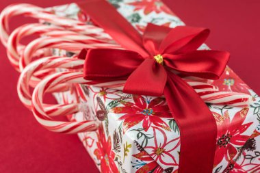 Şeker kutusu Noel kağıt sarma, kırmızı arka plan - Noel için hediye üzerinde kırmızı yay ve şeker kamışı ile dekore edilmiştir. Tebrik kartı kavramı.